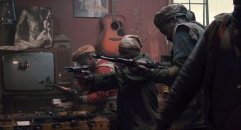 Movie still from “District 9” (2009), directed by Neill Blomkamp – A group of men holding guns in a room with a guitar; Medium shot, Low angle