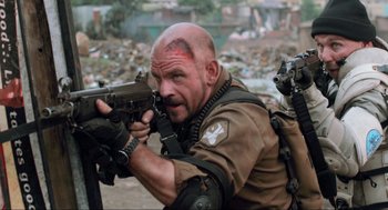Movie still from “District 9” (2009), directed by Neill Blomkamp – A bald man with a gun in his hands; Close Up shot, Over the shoulder angle