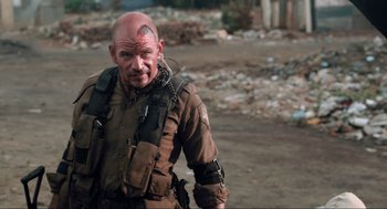 Movie still from “District 9” (2009), directed by Neill Blomkamp – A bald man with a mohawk haircut and tattoos; Close Up shot, Over the shoulder angle