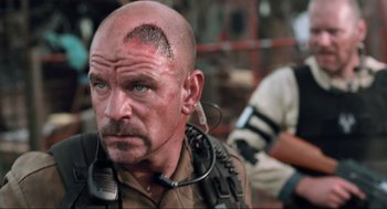 Movie still from “District 9” (2009), directed by Neill Blomkamp – A man with a mohawk haircut is wearing a headset; Close Up shot, Over the shoulder angle