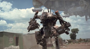 Movie still from “District 9” (2009), directed by Neill Blomkamp – An image of a robot that is in the middle of a field; Wide shot, Low angle