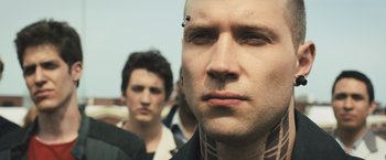 Movie still from “Divergent” (2014), directed by Neil Burger – A person with a piercing on his head; Close Up shot, Over the shoulder angle