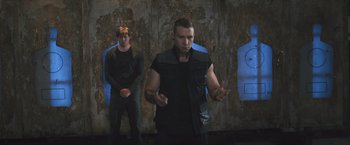 Movie still from “Divergent” (2014), directed by Neil Burger – A man standing next to another man in front of a wall; Medium shot, Low angle
