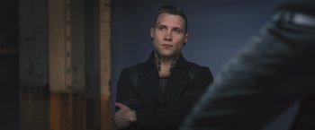 Movie still from “Divergent” (2014), directed by Neil Burger – A man in a black jacket with his arms crossed; Close Up shot, Over the shoulder angle