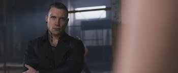 Movie still from “Divergent” (2014), directed by Neil Burger – A man in black jacket standing next to a wall; Close Up shot, Low angle