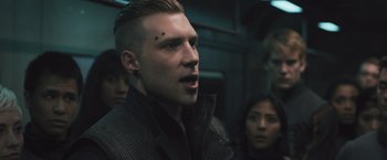 Movie still from “Divergent” (2014), directed by Neil Burger – A man with a shaved head is looking at the camera; Close Up shot, Over the shoulder angle