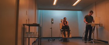 Movie still from “Divergent” (2014), directed by Neil Burger – A woman sitting in a chair in a room; Wide shot, High angle