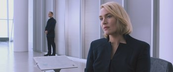 Movie still from “Divergent” (2014), directed by Neil Burger – A woman in a black jacket is standing in a room; Close Up shot, Over the shoulder angle