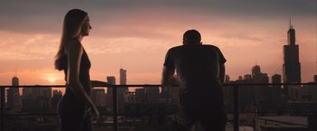 Movie still from “Divergent” (2014), directed by Neil Burger – A man standing on a balcony looking out at a city skyline; Wide shot, Over the shoulder angle