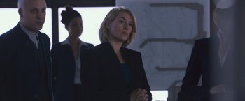 Movie still from “Divergent” (2014), directed by Neil Burger – A woman in a black jacket is standing in a room; Medium shot, Over the shoulder angle
