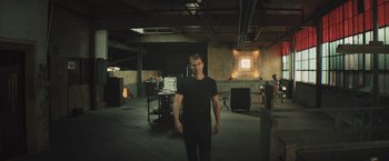 Movie still from “Divergent” (2014), directed by Neil Burger – A man standing in an empty room in a dark place; Wide shot, Low angle