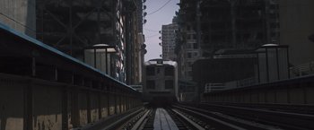 Movie still from “Divergent” (2014), directed by Neil Burger – A train traveling down train tracks next to tall buildings; Extreme Wide shot, High angle