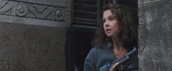 Movie still from “Divergent” (2014), directed by Neil Burger – A woman holding a gun while standing next to a building; Close Up shot, Low angle