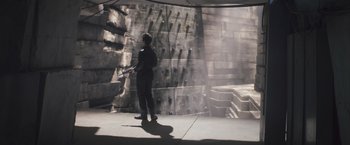 Movie still from “Divergent” (2014), directed by Neil Burger – A man in a black suit is holding a gun; Wide shot, Low angle