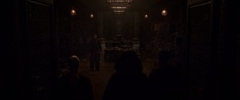 Movie still from “Doctor Strange” (2016), directed by Scott Derrickson – A man standing in front of a group of people in a dark room; Wide shot, Over the shoulder angle