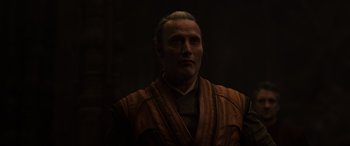 Movie still from “Doctor Strange” (2016), directed by Scott Derrickson – A man in a brown robe is standing in the dark; Close Up shot, Over the shoulder angle