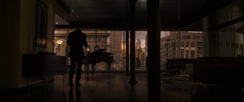 Movie still from “Doctor Strange” (2016), directed by Scott Derrickson – A man standing in front of a piano in front of a large window; Extreme Wide shot, High angle