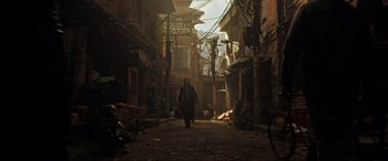 A man walking down a dirt road in a city