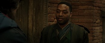 Movie still from “Doctor Strange” (2016), directed by Scott Derrickson – A man in a green shirt and a brick wall; Close Up shot, Over the shoulder angle