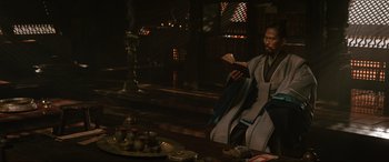 Movie still from “Doctor Strange” (2016), directed by Scott Derrickson – A man sitting at a table with a book in his hands; Medium shot, Over the shoulder angle