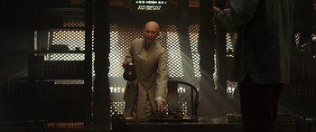 Movie still from “Doctor Strange” (2016), directed by Scott Derrickson – A bald man is standing in front of a stove; Medium shot, Over the shoulder angle