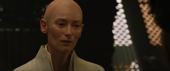 Movie still from “Doctor Strange” (2016), directed by Scott Derrickson – A woman with a bald head is posing for a picture; Close Up shot, Over the shoulder angle