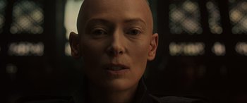Movie still from “Doctor Strange” (2016), directed by Scott Derrickson – A woman with a shaved head is looking at the camera; Close Up shot, High angle