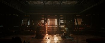 Movie still from “Doctor Strange” (2016), directed by Scott Derrickson – Two people sitting on the ground in front of a building; Wide shot, Low angle