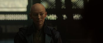 Movie still from “Doctor Strange” (2016), directed by Scott Derrickson – A man with bald head wearing a black jacket; Close Up shot, Over the shoulder angle