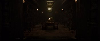Movie still from “Doctor Strange” (2016), directed by Scott Derrickson – A dark room with a table , chairs , and a bicycle; Extreme Wide shot, Low angle