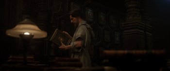 Movie still from “Doctor Strange” (2016), directed by Scott Derrickson – A man in a robe holding a book in his hands; Medium shot, Low angle