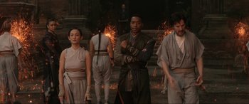Movie still from “Doctor Strange” (2016), directed by Scott Derrickson – A group of people standing next to each other in front of fire; Medium shot, Over the shoulder angle