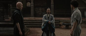 Movie still from “Doctor Strange” (2016), directed by Scott Derrickson – A man in a robe stands in front of a building; Wide shot, Over the shoulder angle