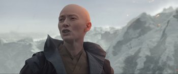 Movie still from “Doctor Strange” (2016), directed by Scott Derrickson – A bald man with a shaved head is standing in front of some mountains; Close Up shot, Over the shoulder angle