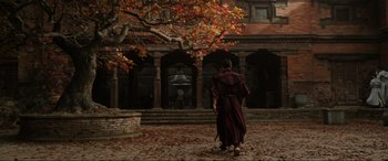 Movie still from “Doctor Strange” (2016), directed by Scott Derrickson – A man in a long red robe walking in front of a building; Wide shot, Low angle