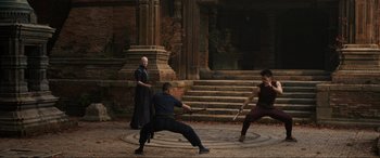 Movie still from “Doctor Strange” (2016), directed by Scott Derrickson – A group of people in a courtyard with a building in the background; Wide shot, Over the shoulder angle