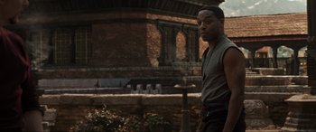 Movie still from “Doctor Strange” (2016), directed by Scott Derrickson – A man standing in front of a brick building; Medium shot, Over the shoulder angle