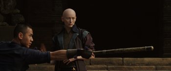 Movie still from “Doctor Strange” (2016), directed by Scott Derrickson – A bald man holding a baseball bat in front of another man; Medium shot, Over the shoulder angle