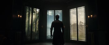 Movie still from “Doctor Strange” (2016), directed by Scott Derrickson – A man standing in front of a window looking outside; Wide shot, Low angle