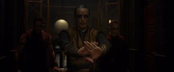 Movie still from “Doctor Strange” (2016), directed by Scott Derrickson – A man with a face paint on his face is holding his hands out; Medium shot, Over the shoulder angle