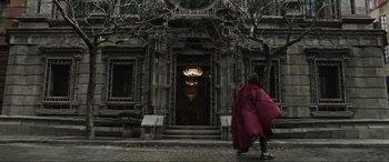 Movie still from “Doctor Strange” (2016), directed by Scott Derrickson – A person walking in front of an old building; Wide shot, Low angle