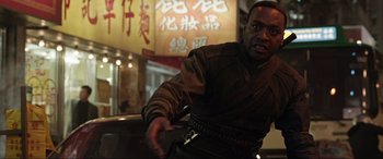 Movie still from “Doctor Strange” (2016), directed by Scott Derrickson – A man in a black shirt and a black belt is in front of a chinese sign; Medium shot, Over the shoulder angle