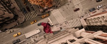 Movie still from “Doctor Strange in the Multiverse of Madness” (2022), directed by Sam Raimi – An aerial view of a city street with a person in a red coat; Extreme Wide shot, Overhead angle