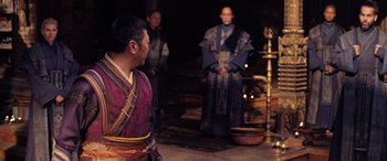 Movie still from “Doctor Strange in the Multiverse of Madness” (2022), directed by Sam Raimi – Three men in traditional garb stand in front of a fountain; Medium shot, Over the shoulder angle