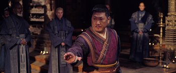 Movie still from “Doctor Strange in the Multiverse of Madness” (2022), directed by Sam Raimi – A man in a purple and red robe holding something in his hand; Medium shot, Over the shoulder angle