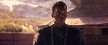 Movie still from “Doctor Strange in the Multiverse of Madness” (2022), directed by Sam Raimi – A man with a dreadlocks standing in front of a building; Close Up shot, Over the shoulder angle