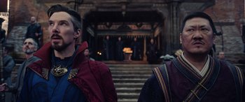 Movie still from “Doctor Strange in the Multiverse of Madness” (2022), directed by Sam Raimi – Two people standing next to each other in front of a stage; Medium shot, Over the shoulder angle