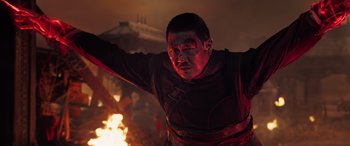 Movie still from “Doctor Strange in the Multiverse of Madness” (2022), directed by Sam Raimi – A man in a red shirt is holding a sword in front of a fire; Medium shot, Low angle