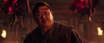 Movie still from “Doctor Strange in the Multiverse of Madness” (2022), directed by Sam Raimi – An asian man with bruises on his face; Close Up shot, Low angle