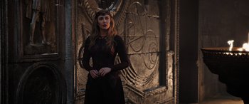 Movie still from “Doctor Strange in the Multiverse of Madness” (2022), directed by Sam Raimi – A woman in a black dress standing in front of a wall; Medium shot, Over the shoulder angle